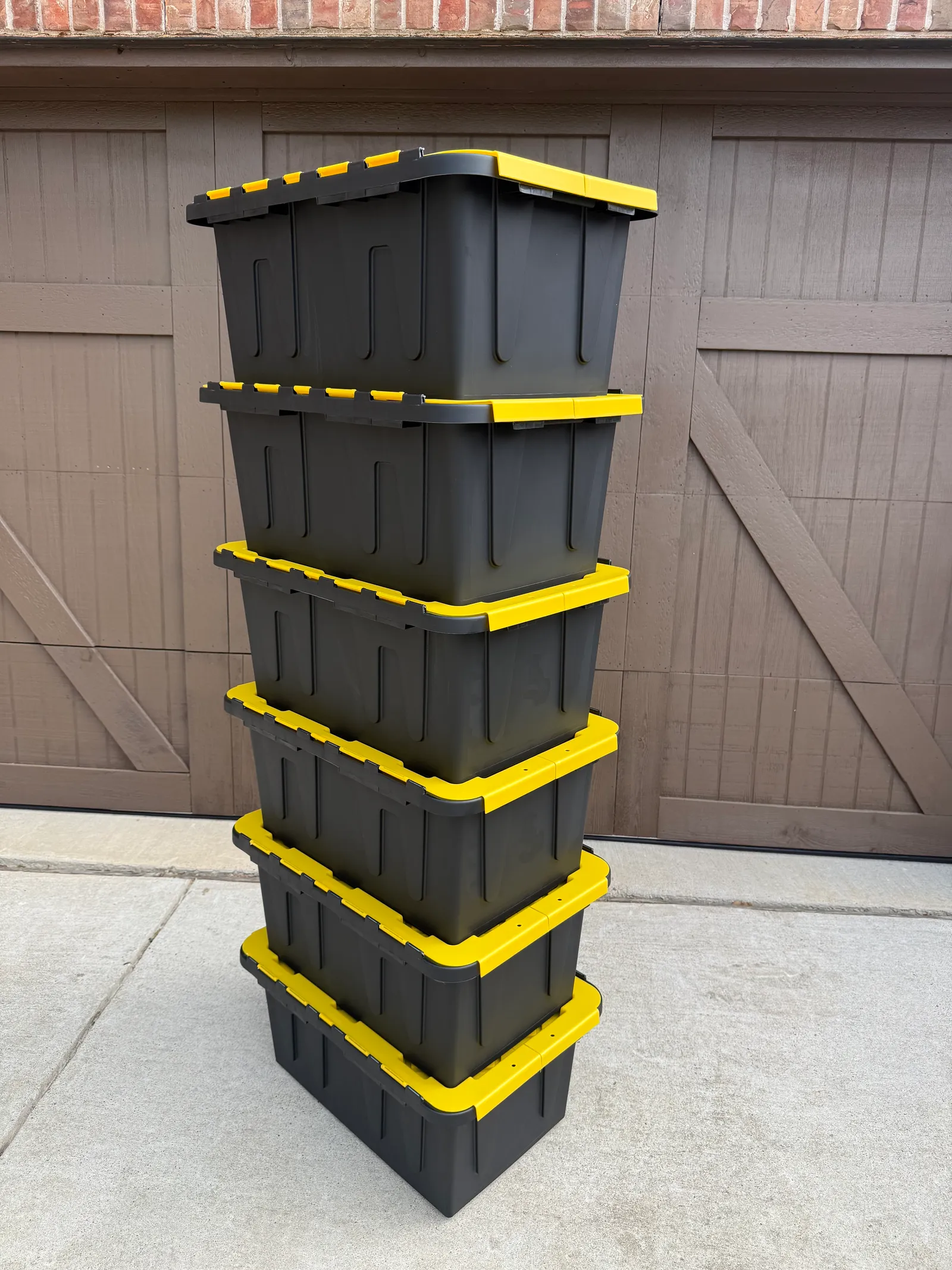 Yellow/Green moving bins stacked by a garage